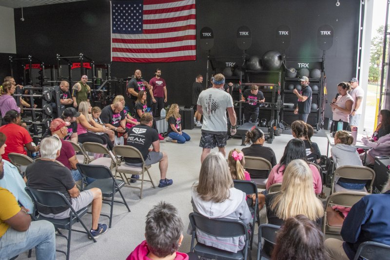 Members of Peak Fitness and guests gather to cheer for lifters participating in the breast cancer fundraiser.